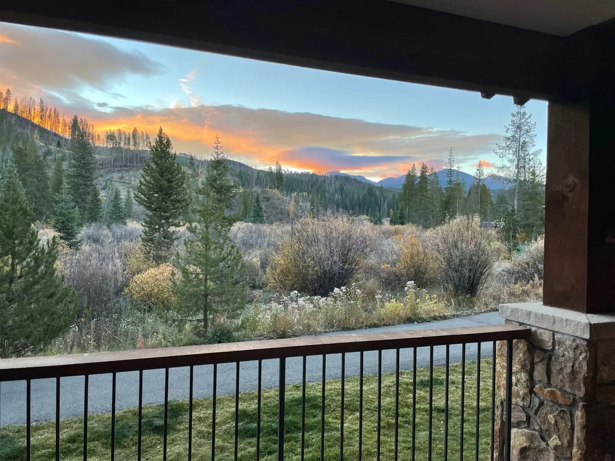 A tranquil exterior landscape featuring lush greenery, rolling hills, and majestic mountains under a vivid sunset sky. The scene feels alive with the possibility of hiking, mountain biking, and nature walks, encapsulating the spirit of summer adventure.